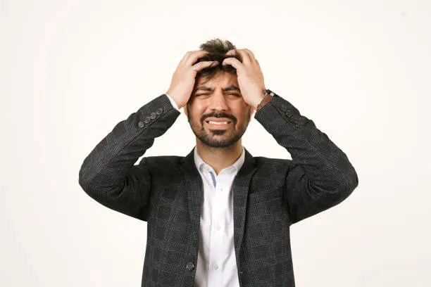 Stressed man holding his head, expressing anxiety, frustration, or mental overload