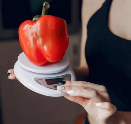 Bell pepper on kitchen scale, symbolizing calorie utilization and nutrition control

