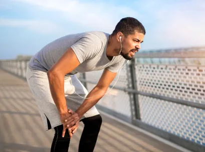 Man resting with hands on knees, showing fatigue and chronic pain after exercise