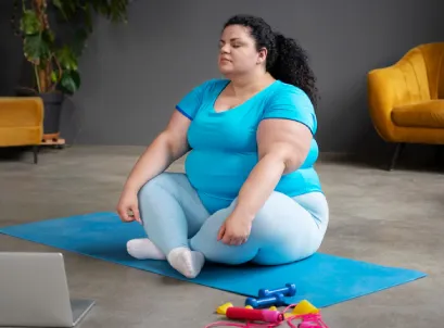 Woman sitting on yoga mat at home, representing excess weight and wellness focus