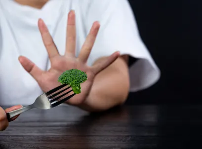 Child refusing broccoli by holding up hand, showing food aversion or picky eating