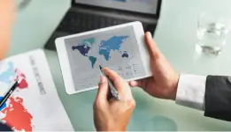 Hands using tablet with world map data and charts during business analysis
