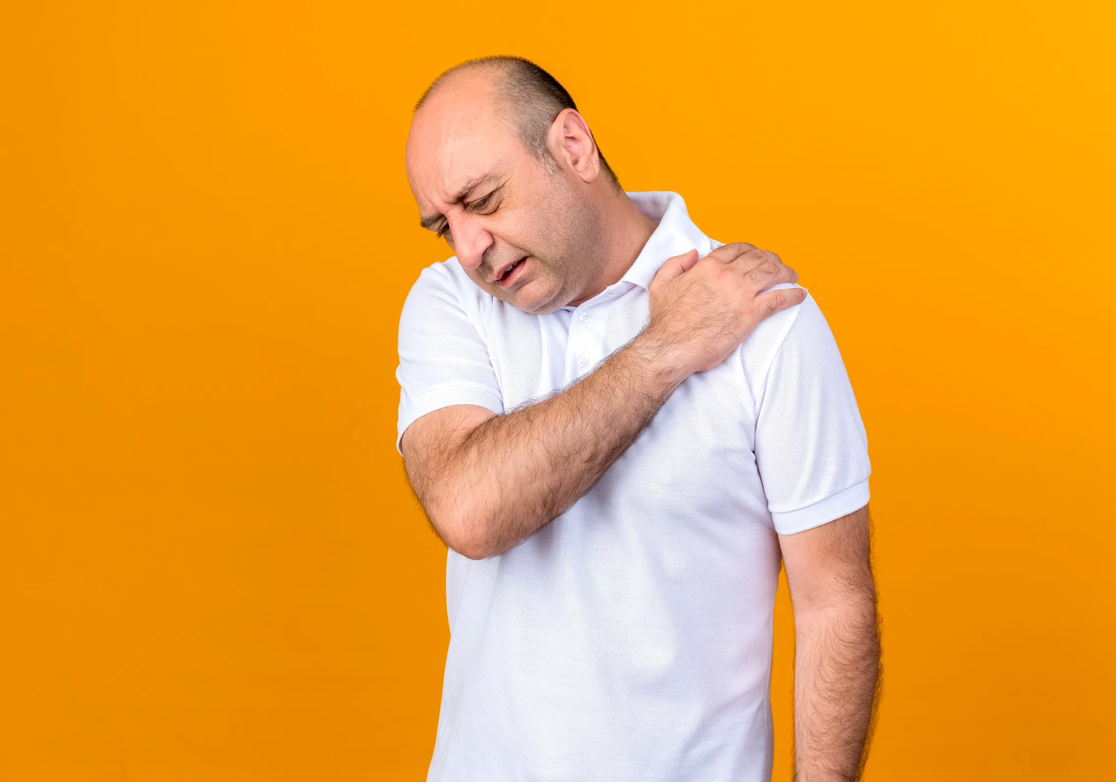 Man holding shoulder in pain, showing muscle strain or physical discomfort
