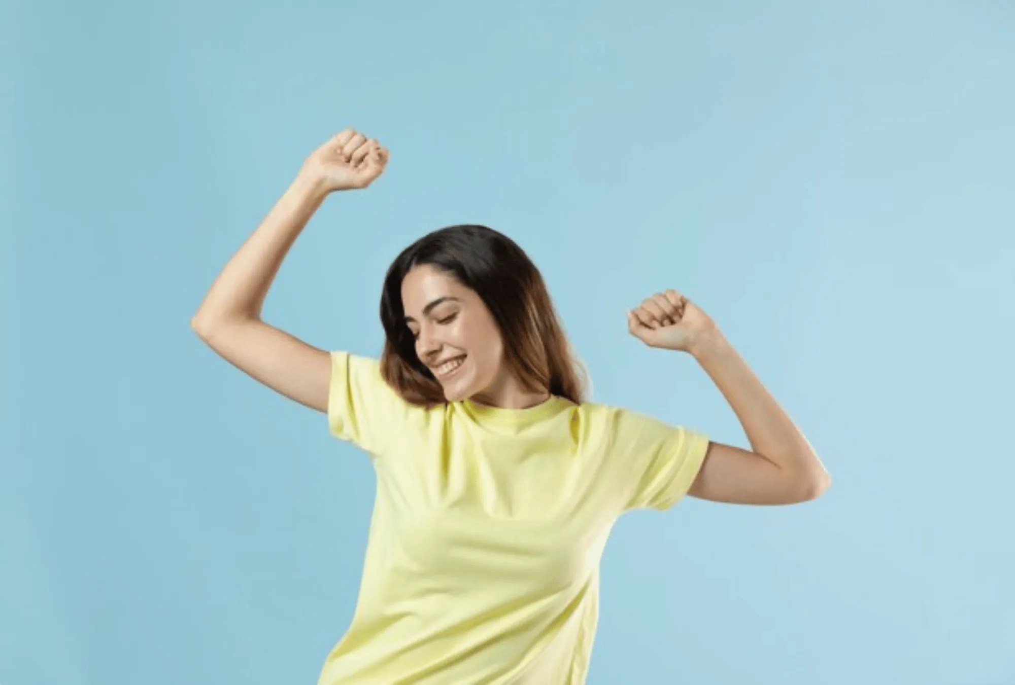 Happy woman dancing with raised arms, expressing energy, joy, and positivity
