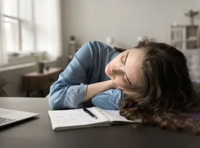 Woman resting head on desk from exhaustion, representing chronic fatigue and low energy