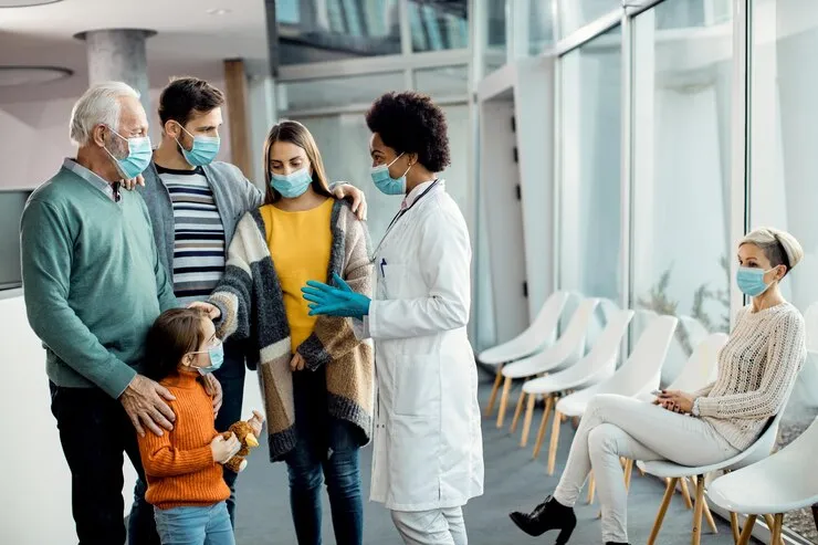 Doctor consulting family in clinic waiting area, representing patient care and healthcare support
        