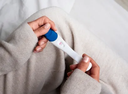 Hands holding positive pregnancy test, suggesting pregnancy confirmation at home