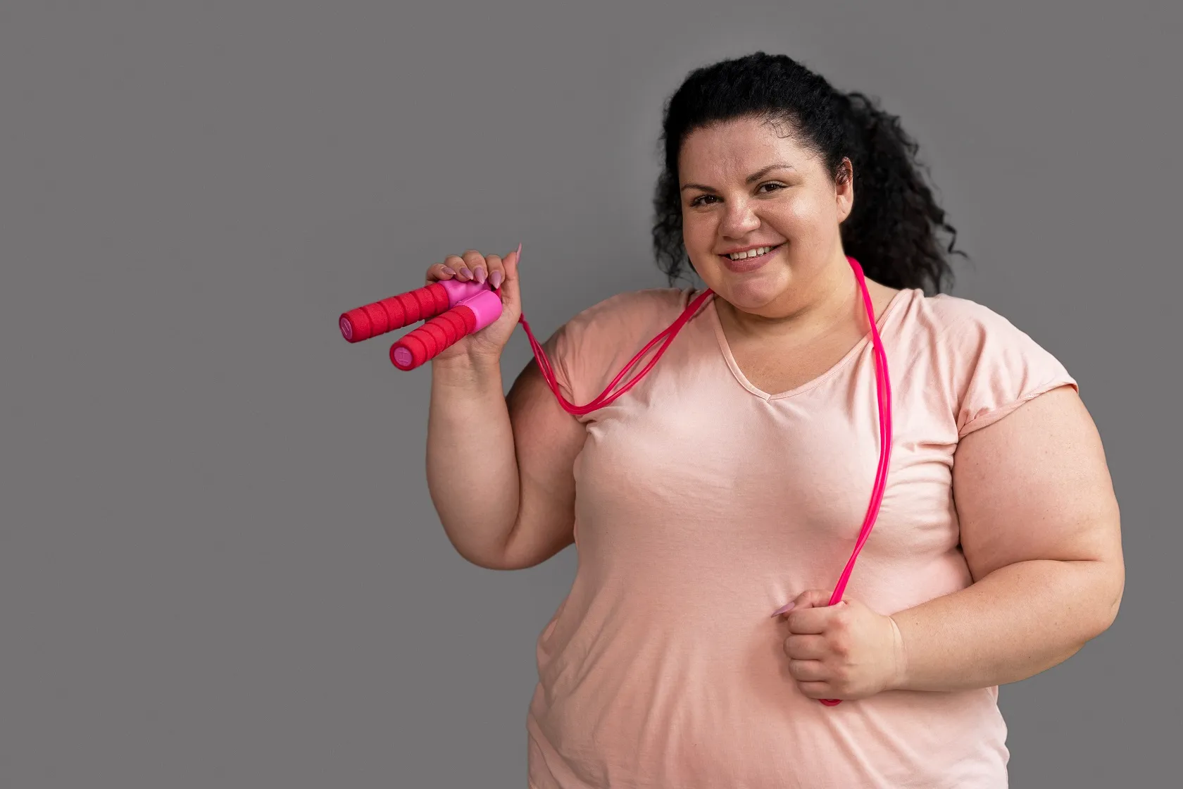 Smiling woman holding jump rope, representing fitness, exercise, and wellness

