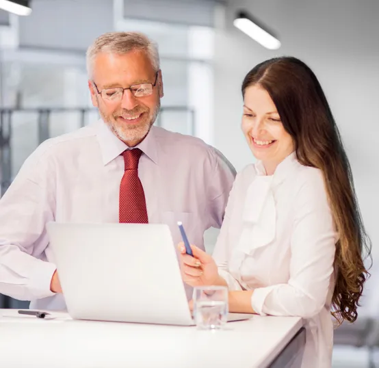 Two professionals reviewing information together on a laptop, showing teamwork and collaboration
      
