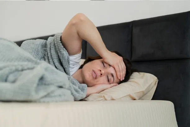 Person lying in bed holding head, showing headache, stress, or poor sleep
